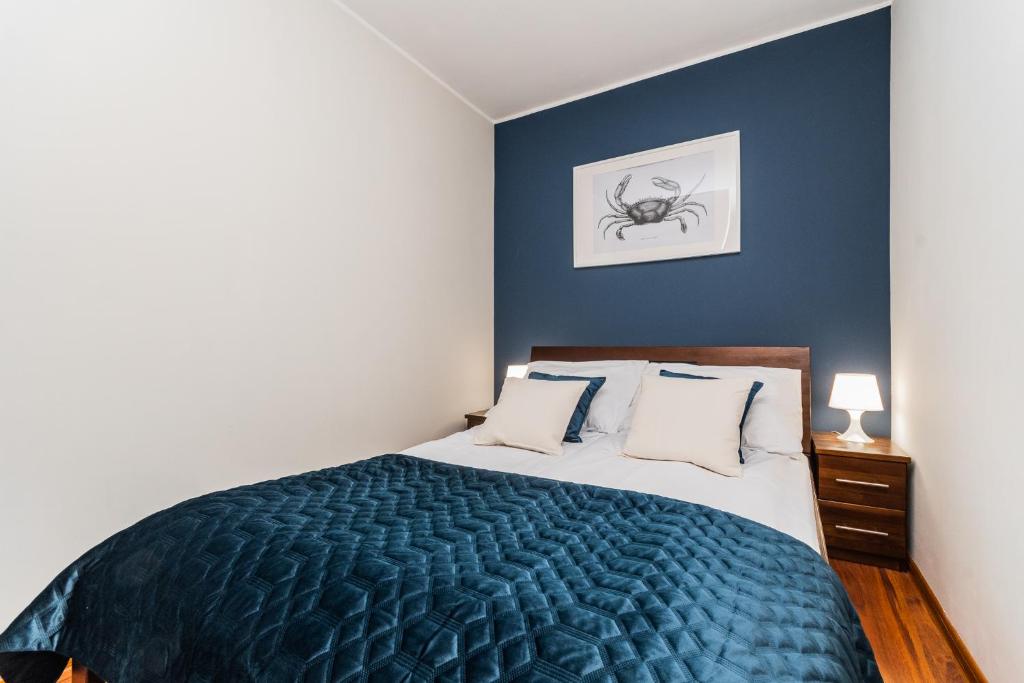 Un dormitorio con una cama tamaño king con paredes azules. en Flatbook Apartamenty - Port Stegna z Parkingiem, en Stegna