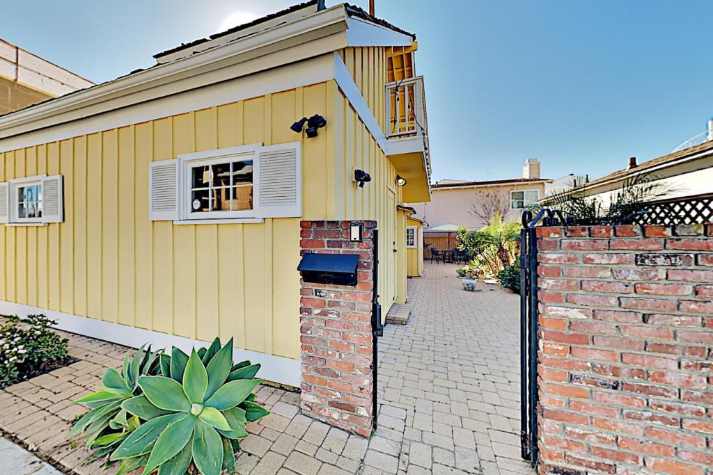 una casa amarilla con una pared de ladrillo y una puerta en Relaxation Station, en Corona del Mar