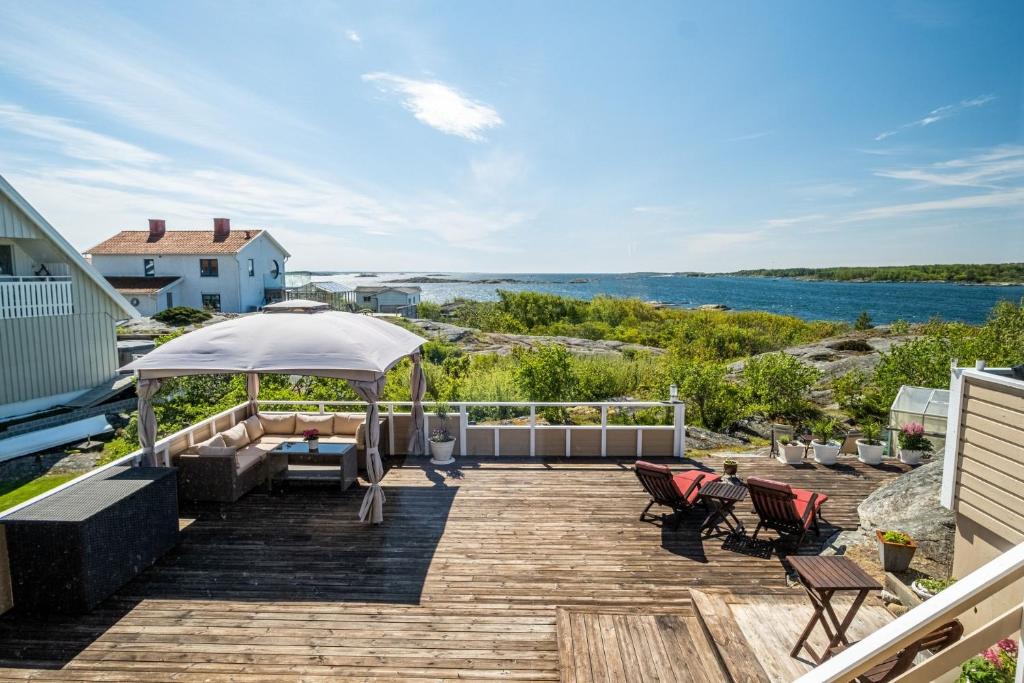 um deque com cadeiras e um guarda-sol e a água em Large and cozy accommodation on Donsö with ocean view em Donsö