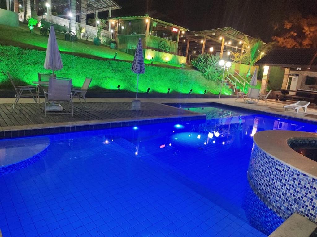 Chalés Marinelli em São Roque في ساو روكي: حمام سباحة في الليل مع أضواء خضراء