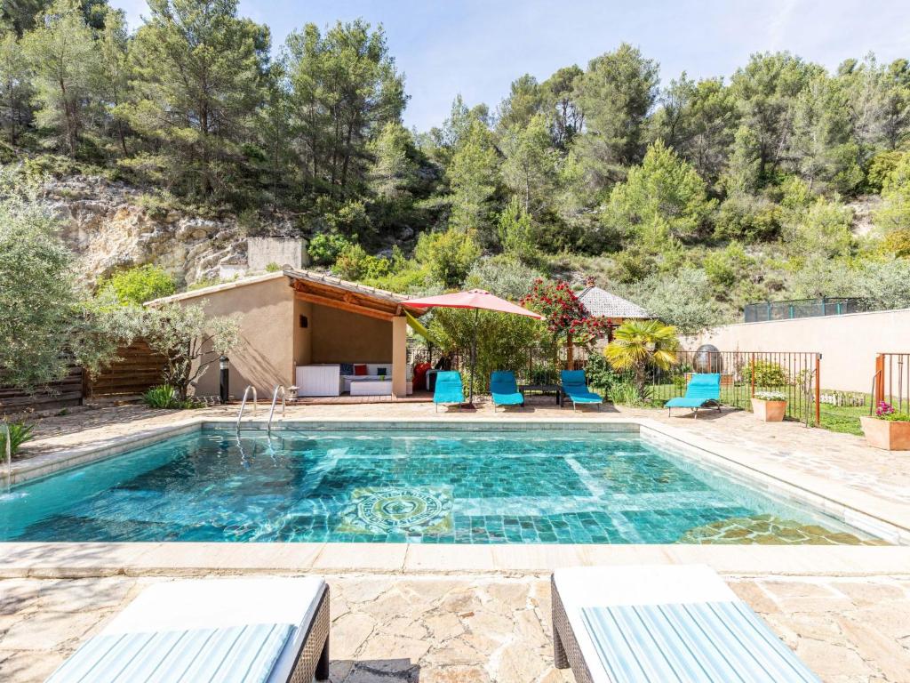 une piscine avec des chaises bleues et une maison dans l'établissement Villa L'Oliveraie by Interhome, à Le Barroux