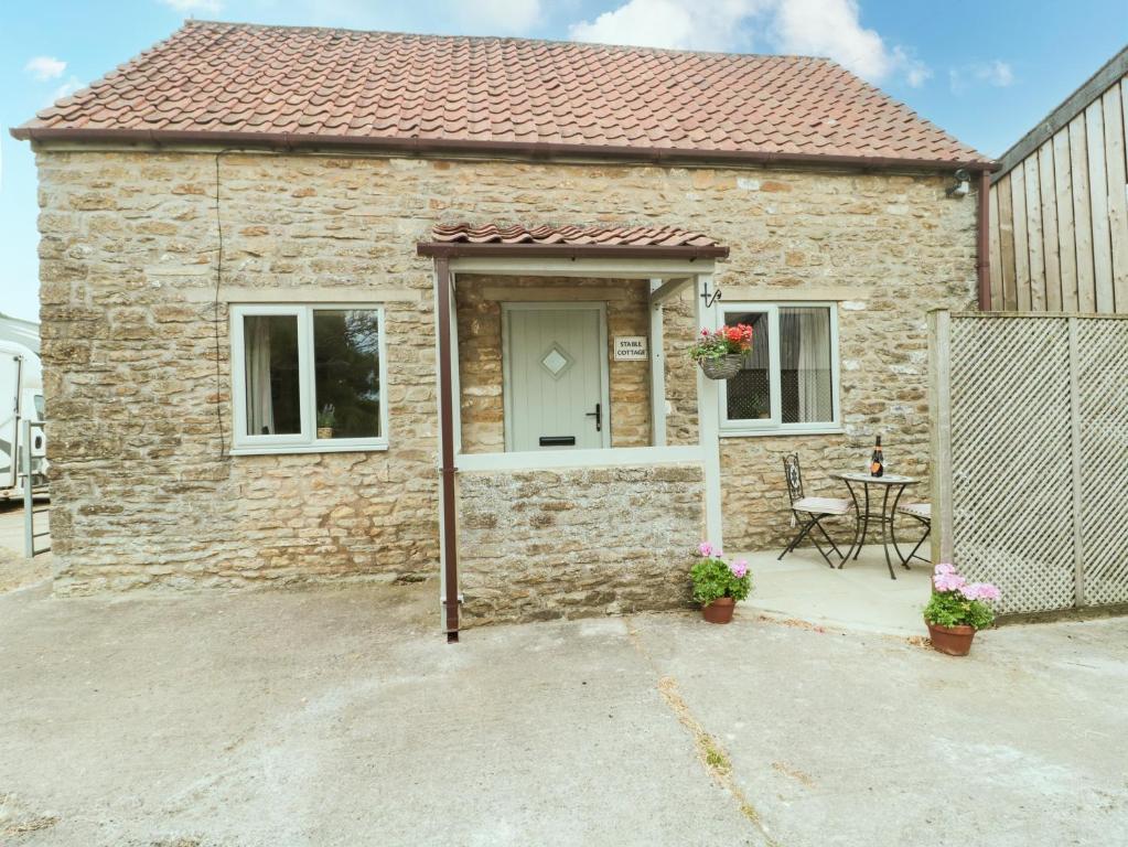 Stable Cottage, Rode Farm في فروم: منزل من الطوب مع طاولة أمامه