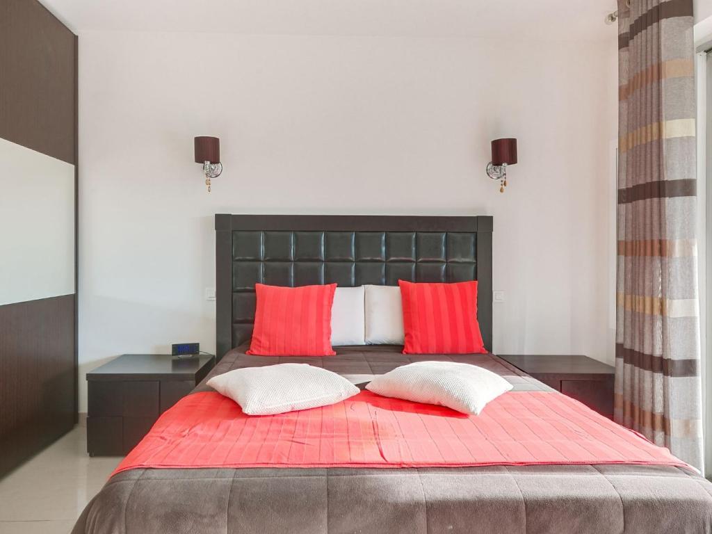 a bedroom with a red bed with two red pillows at Apartment Les Pins D&#39;Alep by Interhome in Le Cannet