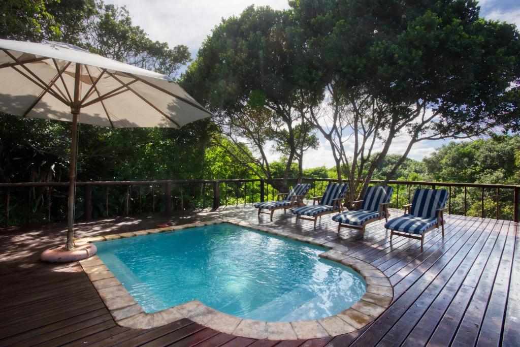 a pool with chairs and an umbrella on a wooden deck at Kangela 10 in Ponta Malongane