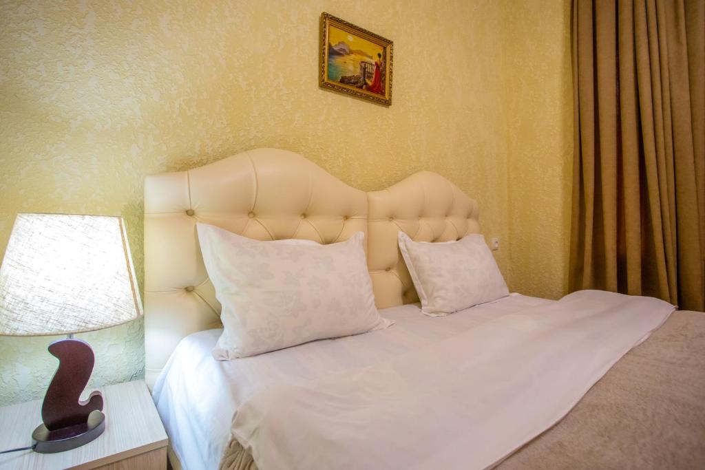 1 dormitorio con 1 cama blanca con cabecero y lámpara en HOTEL VLADi en Kutaisi