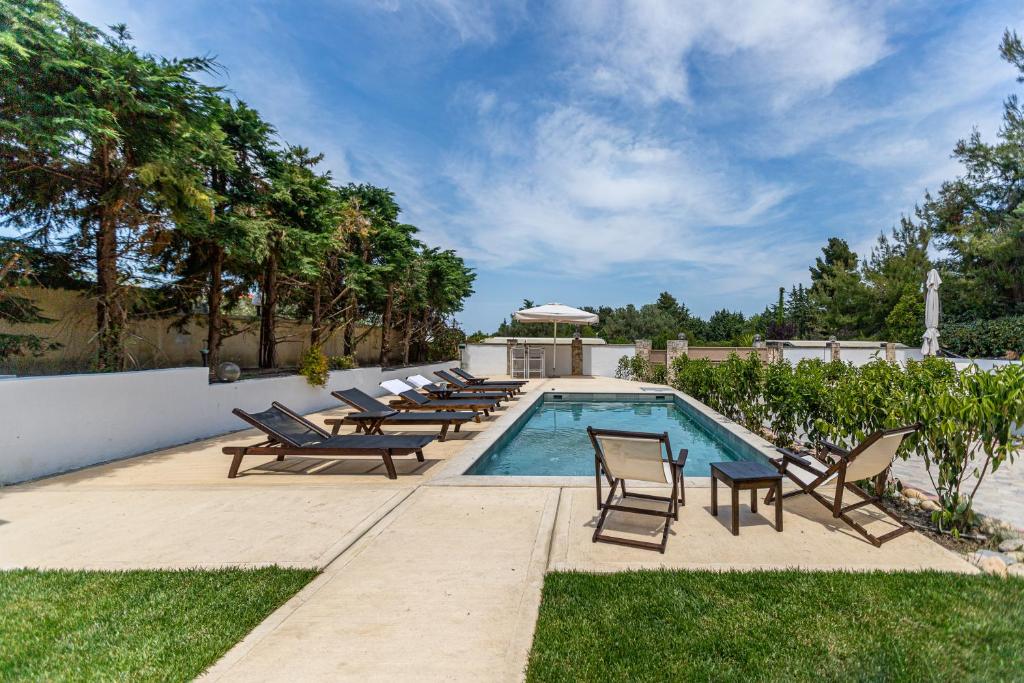 a pool with chaise lounge chairs and a swimming pool at Selia Villa Pefkochori in Pefkochori