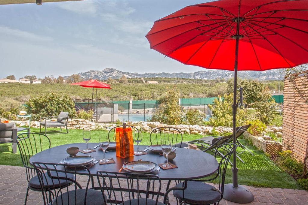 stół z czerwonym parasolem na patio w obiekcie Tramontana quiet place 7 min from beach swimming pool bbq w mieście Calenzana