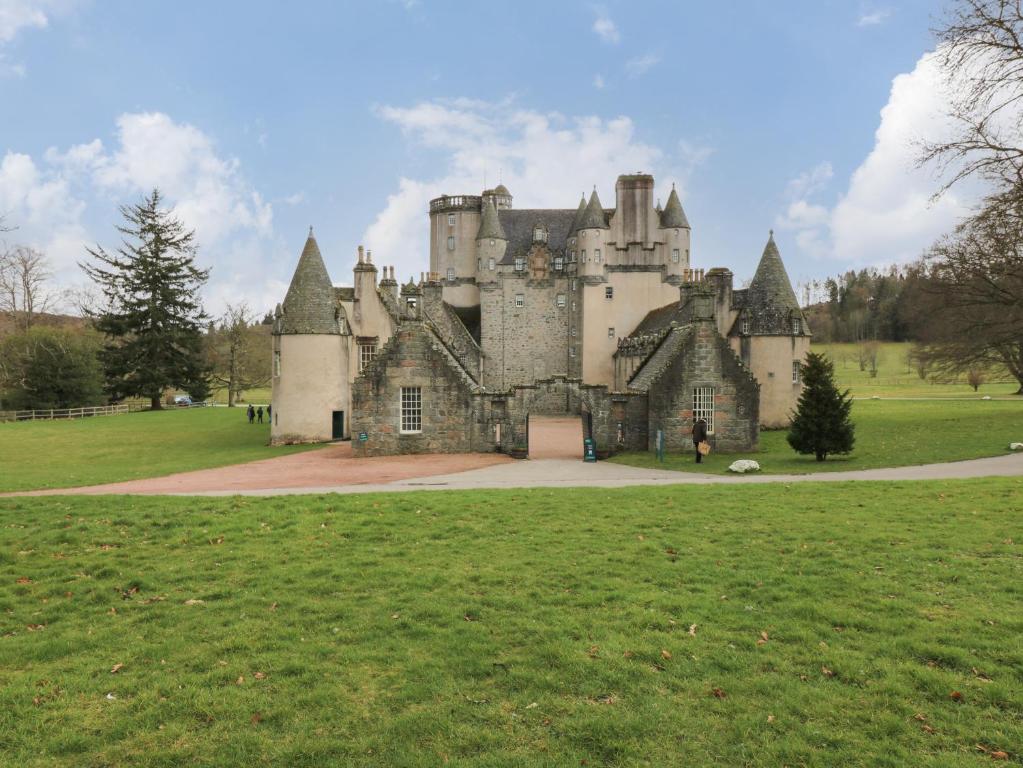 an old castle sitting in a field of grass at East Wing - Castle Fraser in Inverurie