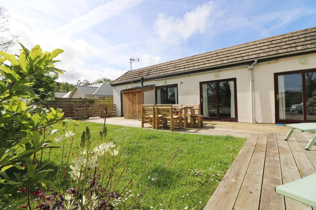 a garden with a wooden deck and a building at Otters Holt in St Merryn