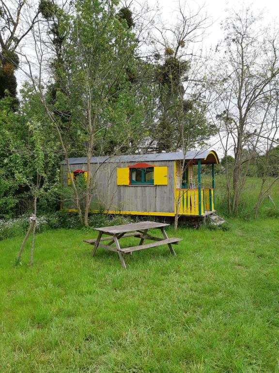 uma mesa de piquenique e uma casa de jogos num campo em Roulotte de l'Aubetin em Saint-Augustin