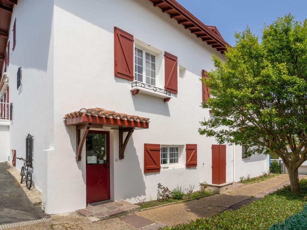 a white house with red shutters and a red door at Apartment Berasteguia-5 by Interhome in Ciboure