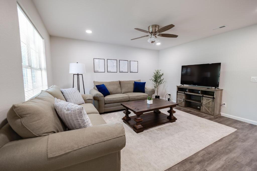 a living room with a couch and a flat screen tv at Trailside Townhouse - Close to Downtown & Bike Trails in Bentonville