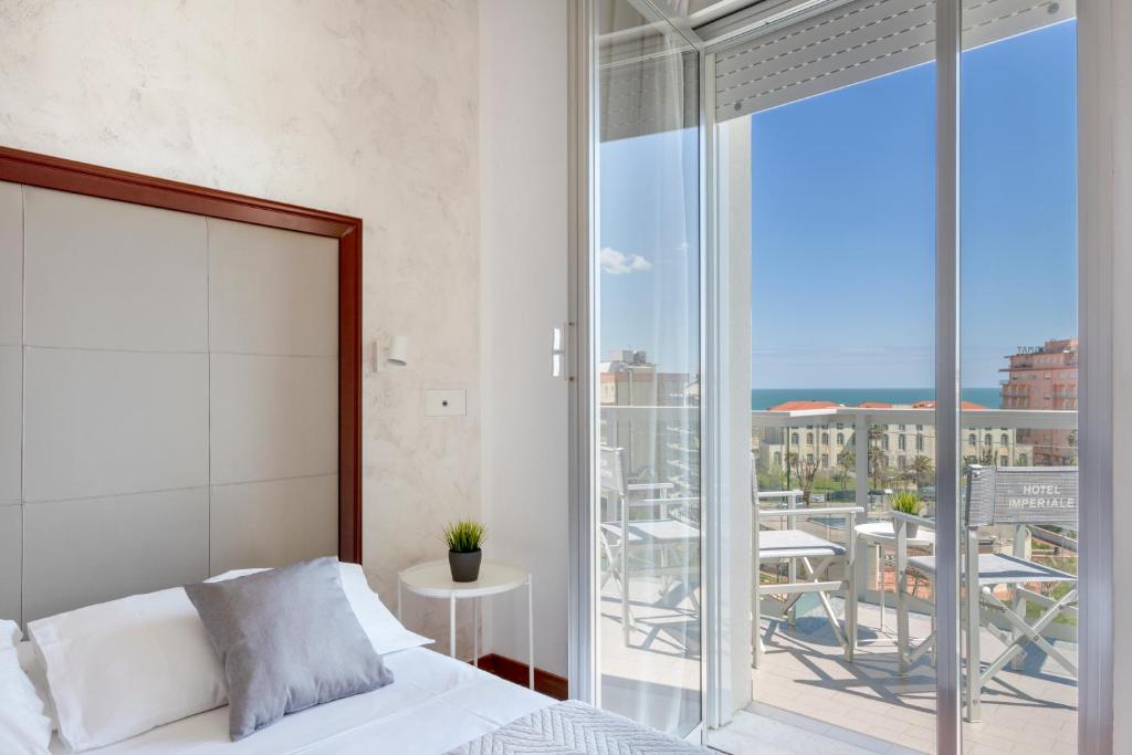 1 dormitorio con cama y vistas a un balcón en Hotel Imperiale, en Cattolica