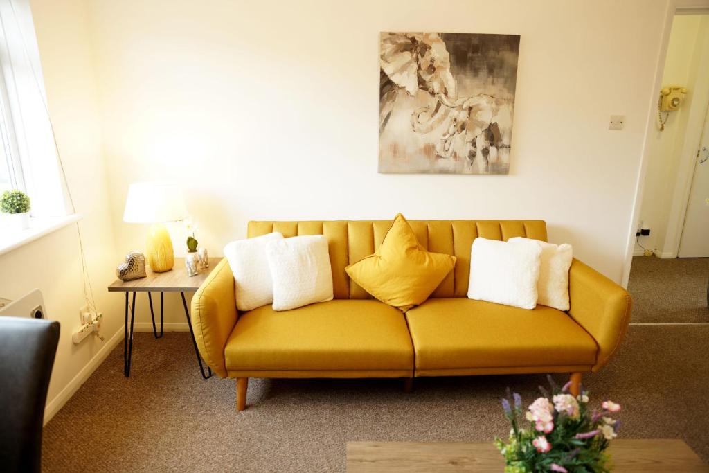 a living room with a yellow couch with pillows at 10BH Dreams Unlimited- Budget Heathrow Long stay Apartment with FREE PARKING in Ashford