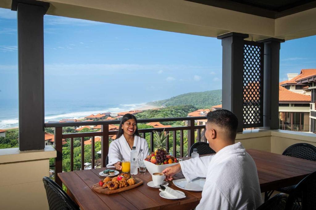 a man and woman sitting at a table with a bowl of food at The Capital Zimbali in Ballito
