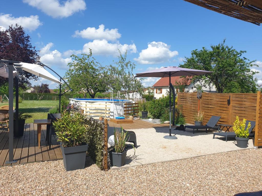 un patio con sillas, una sombrilla y una piscina en Le Heron Pourpre B&B gastronomique, en Cronat