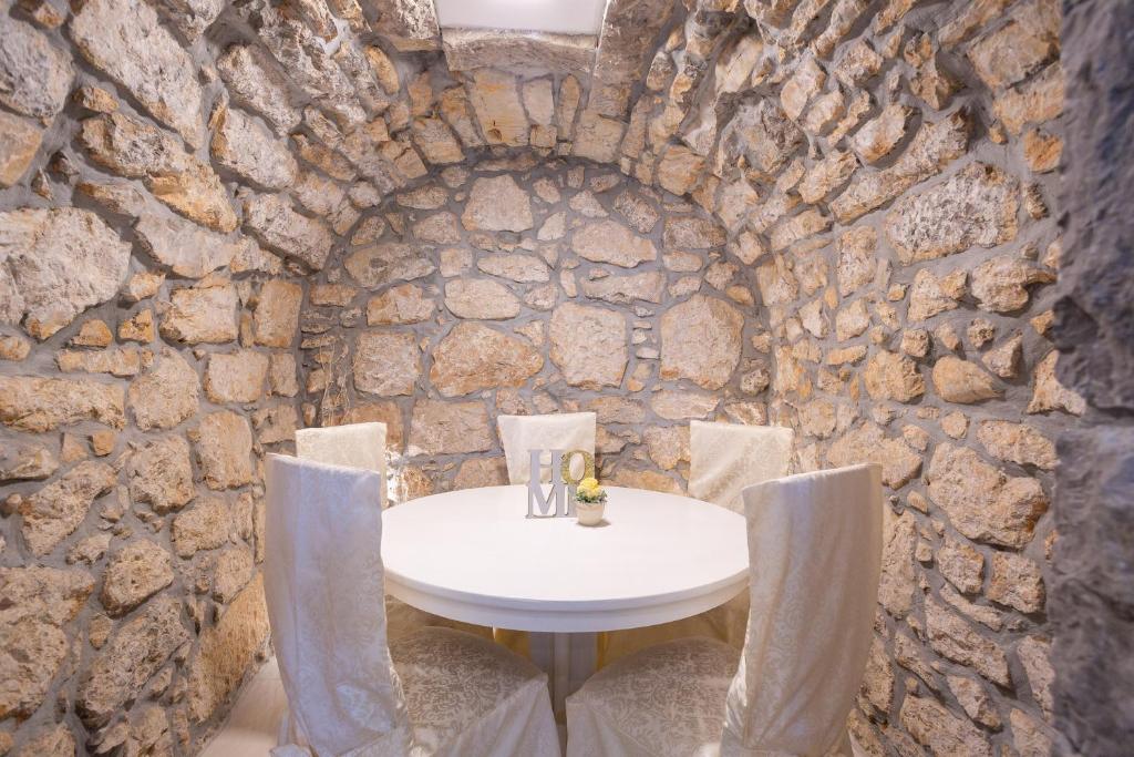 pared de piedra con mesa blanca y sillas en Apartment Tina en Vrh