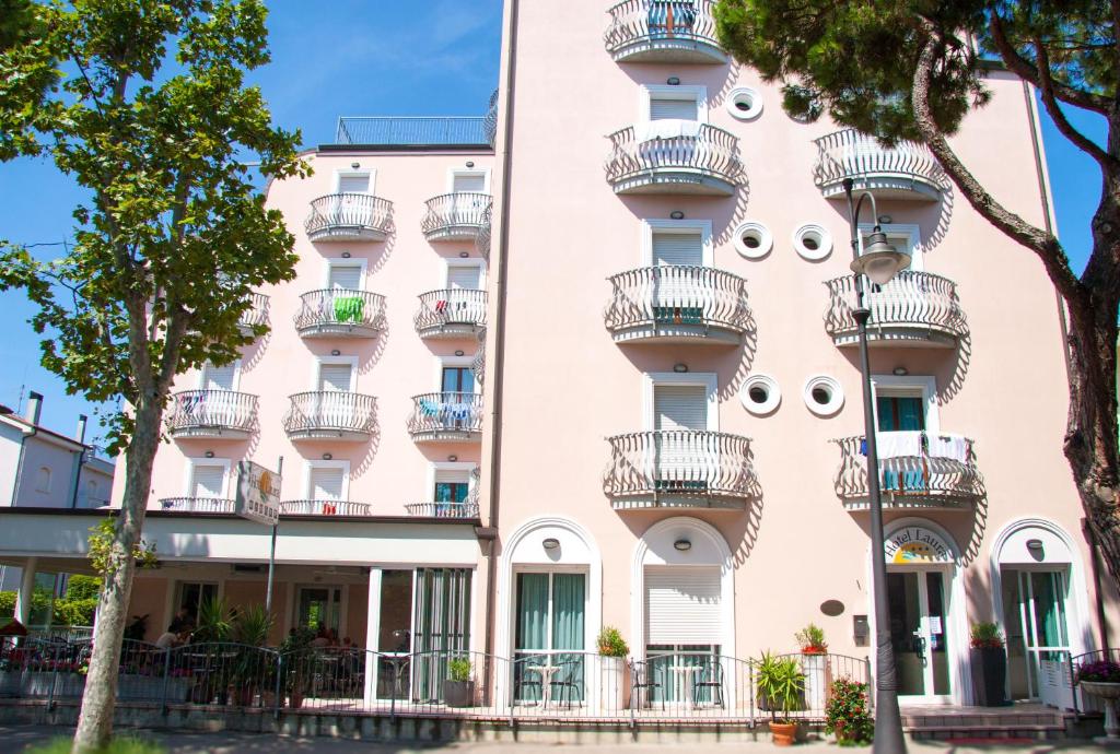 - un bâtiment rose avec balcon dans l'établissement Hotel Laura, à Cesenatico