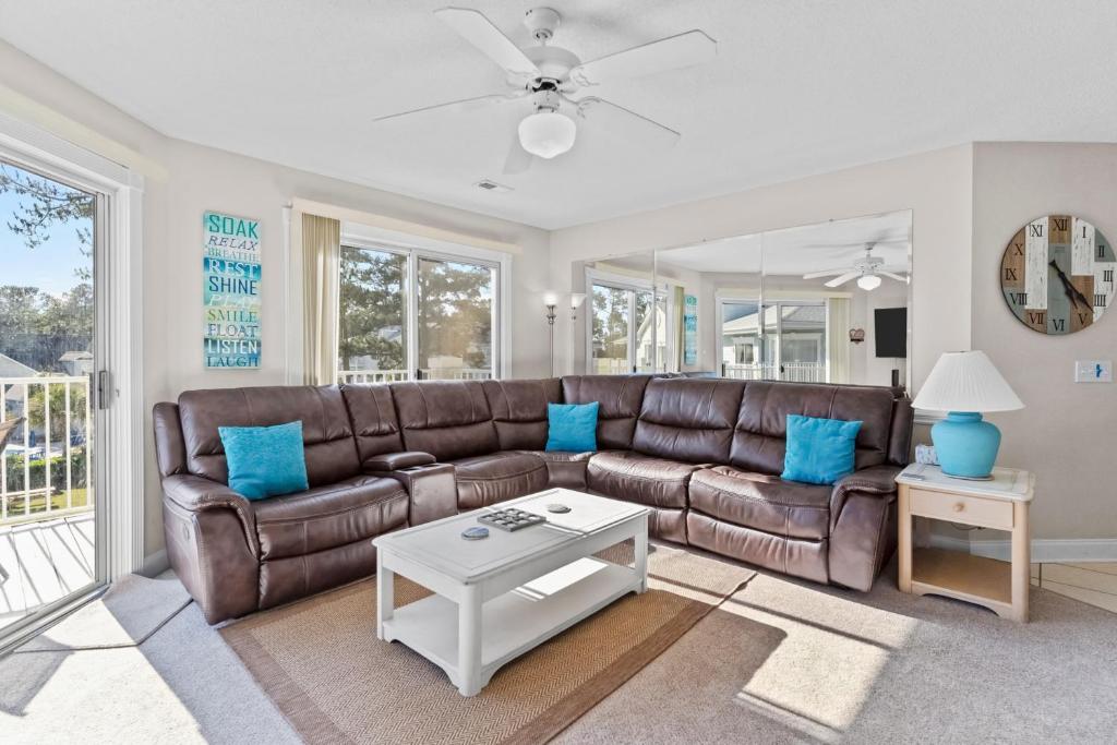 a living room with a brown leather couch and blue pillows at Tee Time Beach Time in Calabash