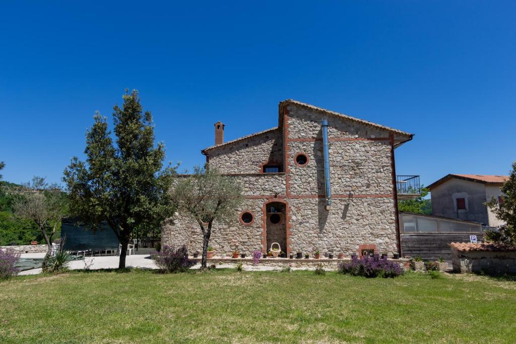 une ancienne maison en pierre avec une cour herbeuse dans l'établissement Agriturismo Locanda Nina - Irpinia, à Montemarano
