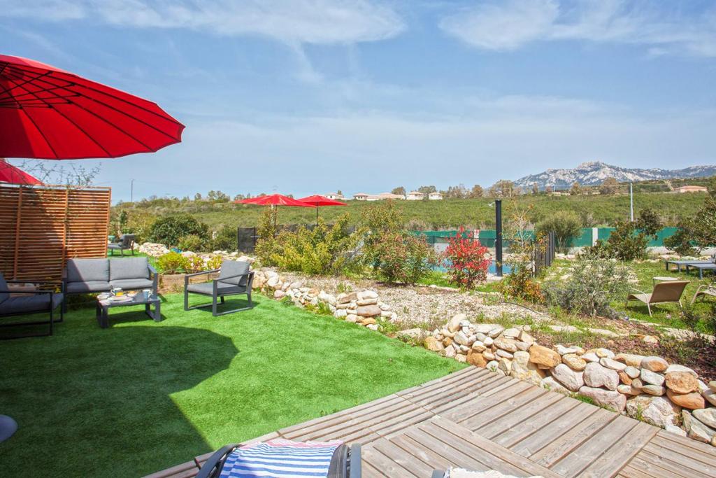 een tuin met een rode parasol en een gazon bij apart Levante shared swimming pool bbq in Calenzana
