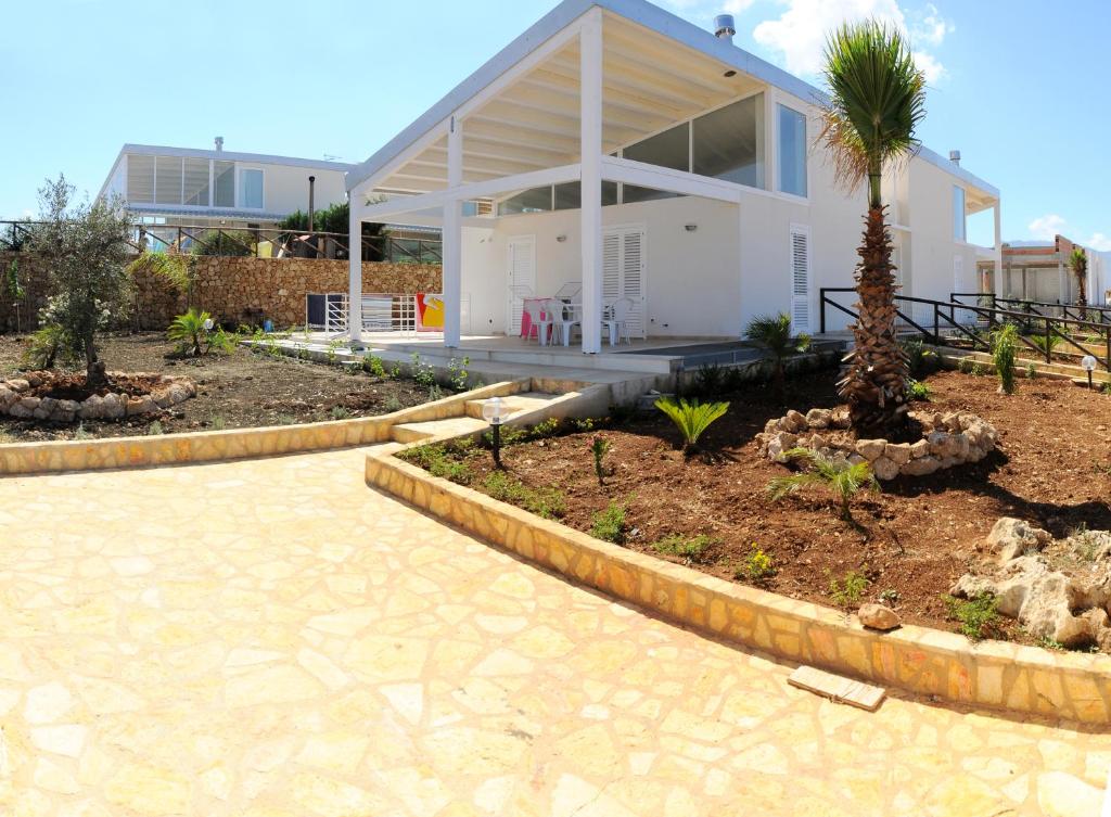 una casa bianca con una palma di fronte di Case Vacanza Viola di Mare a Custonaci