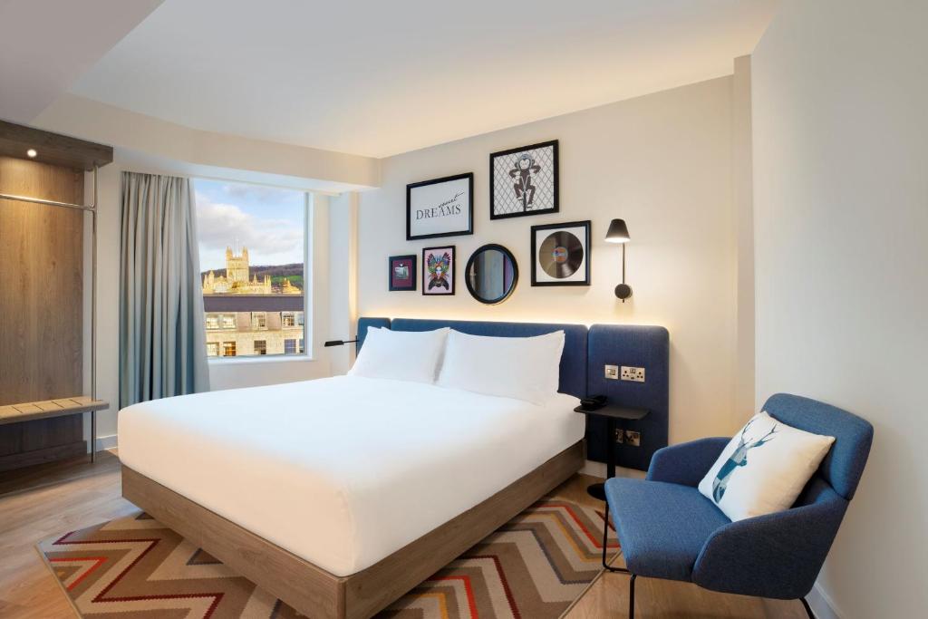 a bedroom with a bed and a chair and a window at Hampton By Hilton Bath City in Bath