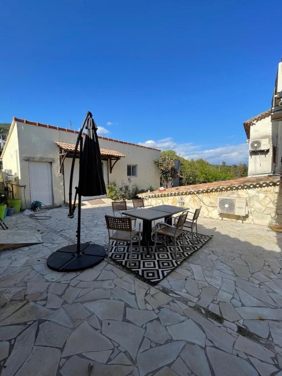 eine Terrasse mit einem Tisch, Stühlen und einem Sonnenschirm in der Unterkunft Mont gozzi in Ajaccio