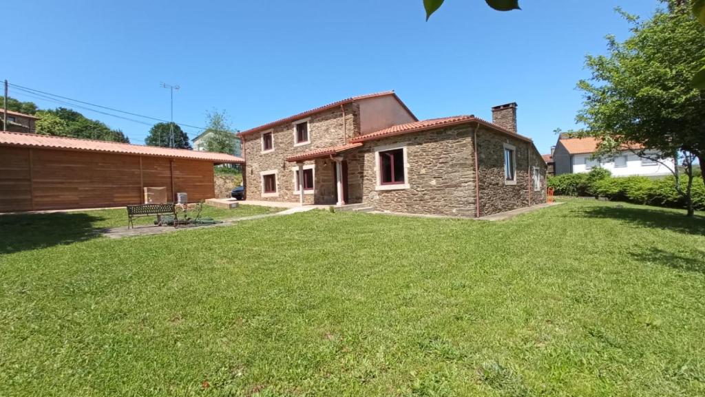 une grande cour avec une maison et un bâtiment dans l'établissement Casa Meiga, à Arzúa