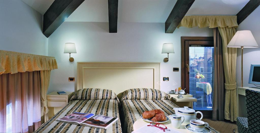 a hotel room with a bed and a table with a tableasonable at Hotel Giudecca Venezia in Venice