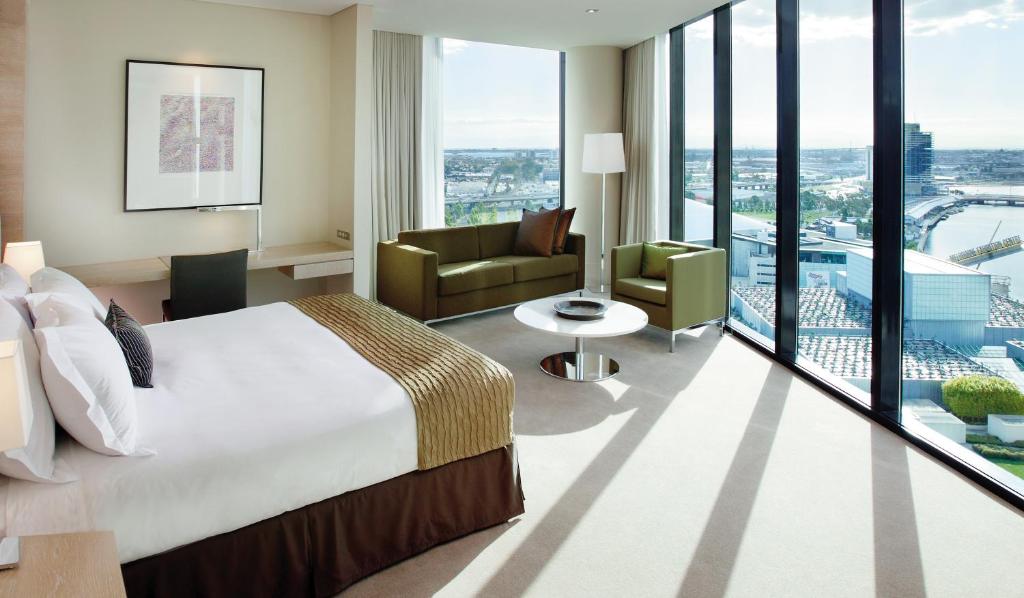 a hotel room with a bed and a living room at Crown Promenade Melbourne in Melbourne