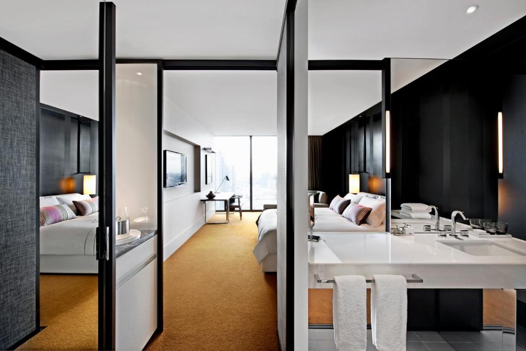 a bathroom with two beds and a sink and a mirror at Crown Metropol Melbourne in Melbourne