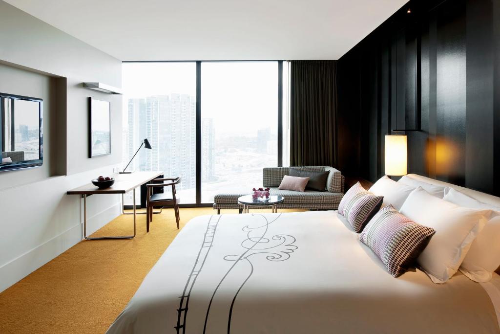 a bedroom with a large bed with a desk and a chair at Crown Metropol Melbourne in Melbourne
