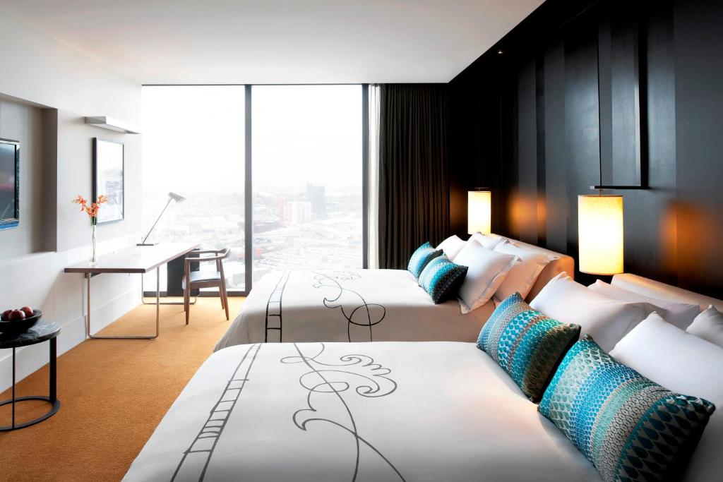 a hotel room with two beds and a desk at Crown Metropol Melbourne in Melbourne