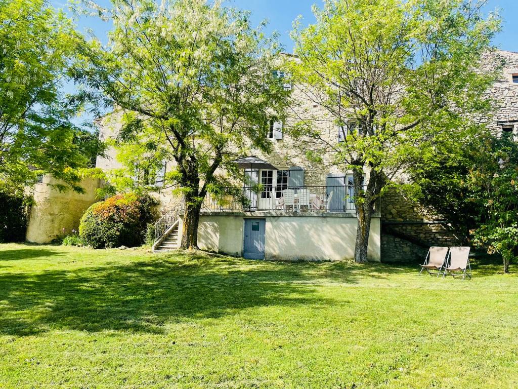 ein Haus mit einem Baum und zwei Stühlen im Hof in der Unterkunft Gîte La Bastide de La Loge au pied du Mont Ventoux in Sault-de-Vaucluse