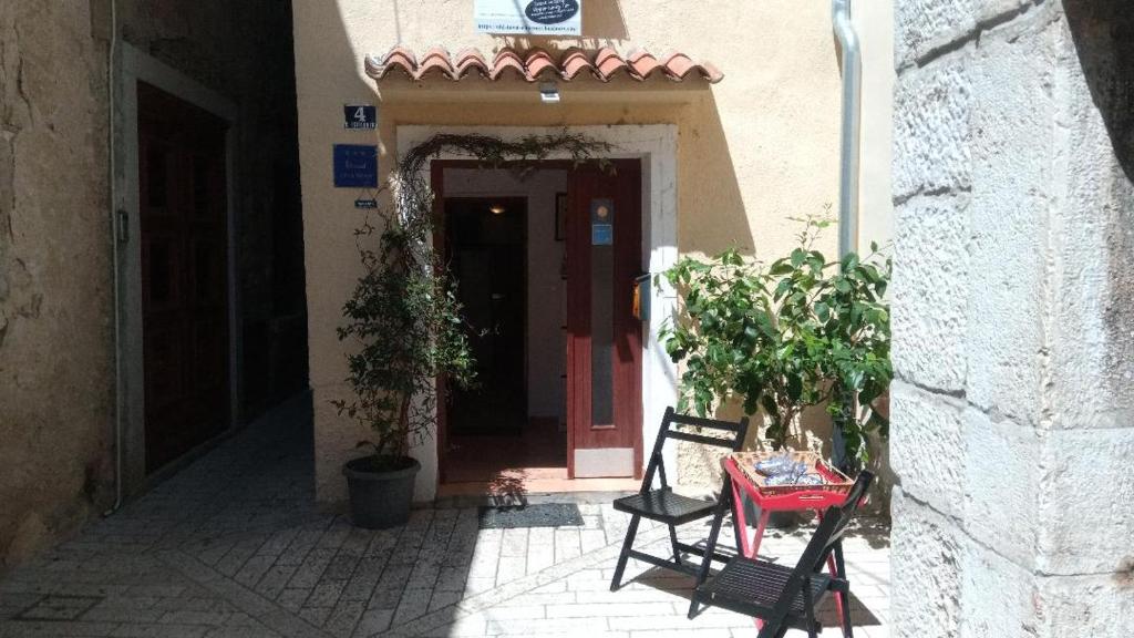 um beco com uma porta vermelha, uma mesa e cadeiras em Old Town Charmer em Poreč