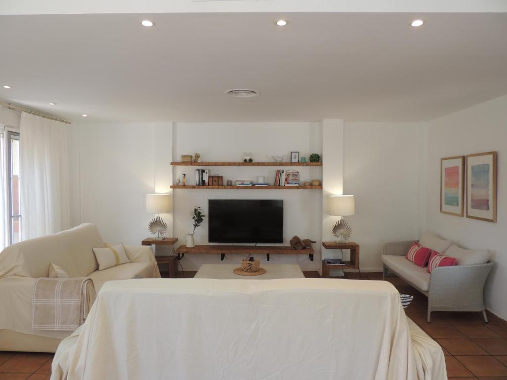 sala de estar blanca con TV y sofá en ACOGEDOR ADOSADO entre mar y montaña en Cullera