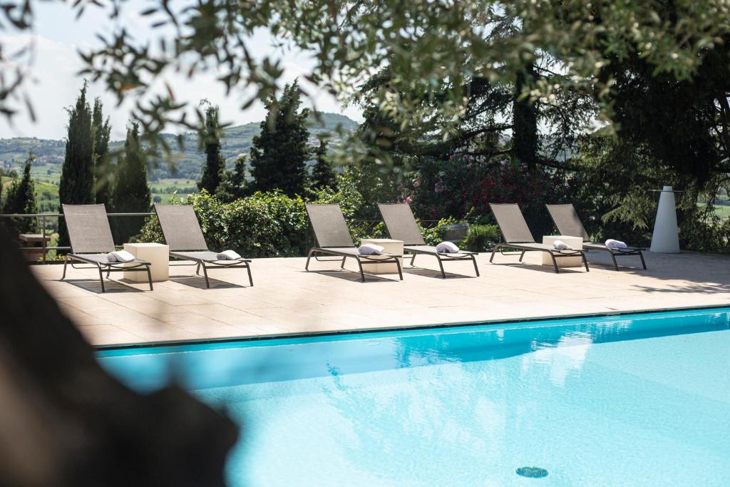 a row of lounge chairs next to a swimming pool at Massimago Wine Relais in Mezzane di Sotto