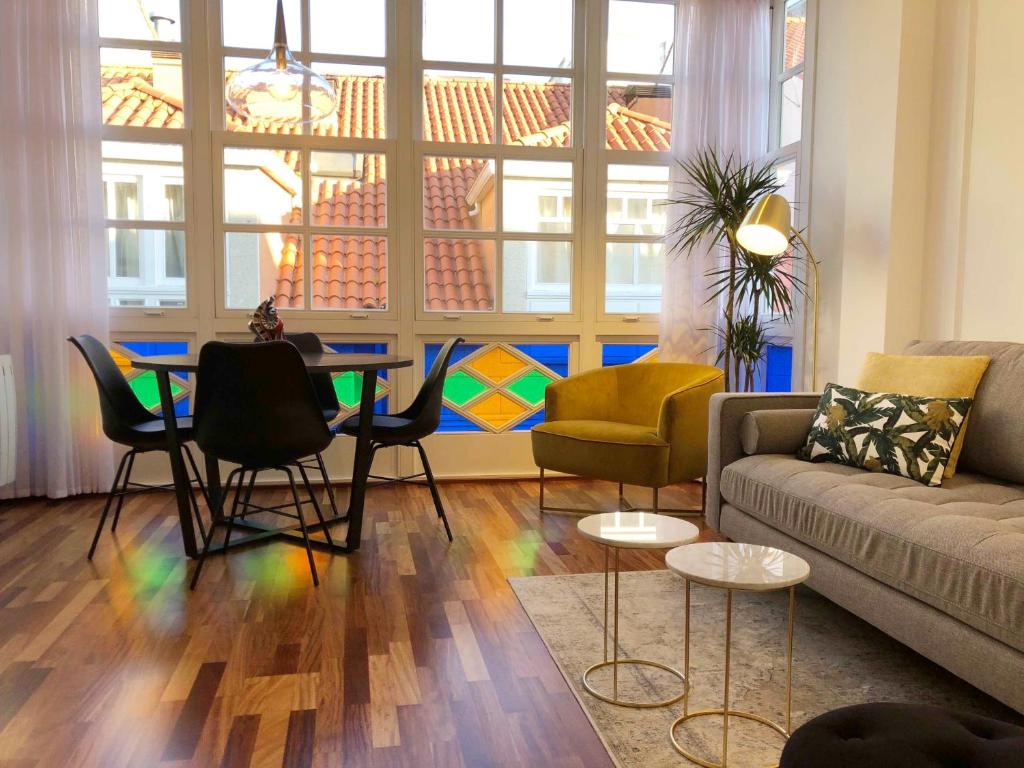 sala de estar con sofá, mesa y sillas en Yuhom casas con alma Galera 3º, en A Coruña