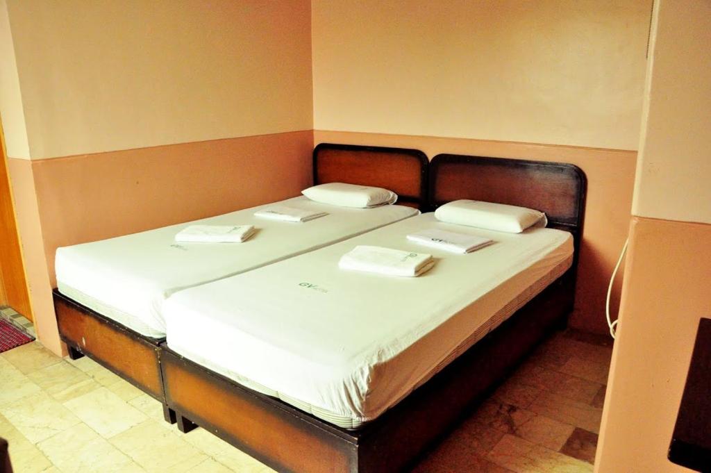 a bed with white sheets and white pillows on it at GV Hotel - Camiguin in Mambajao