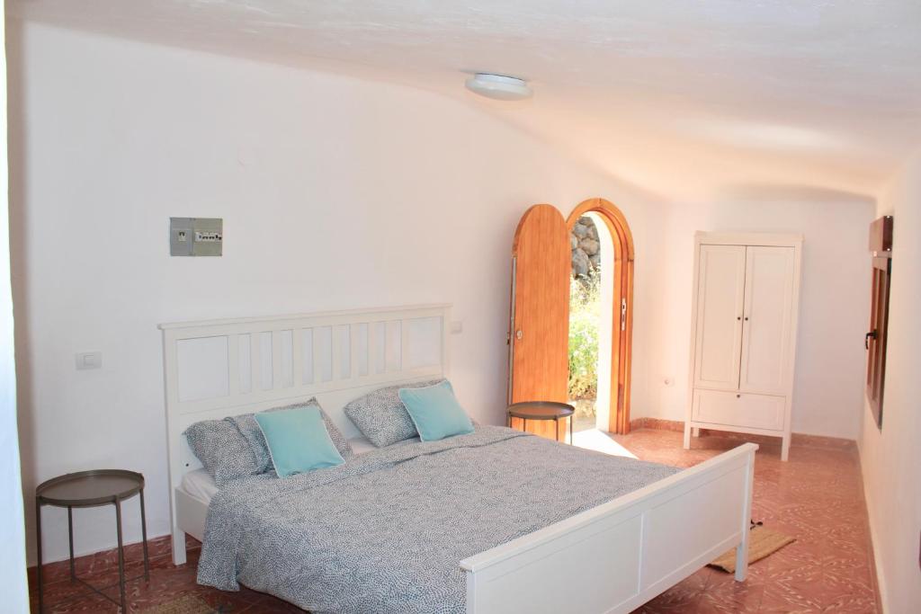 Dormitorio blanco con cama con almohadas azules en Casa-Finca El Maipéz de Tejeda, en Las Palmas de Gran Canaria