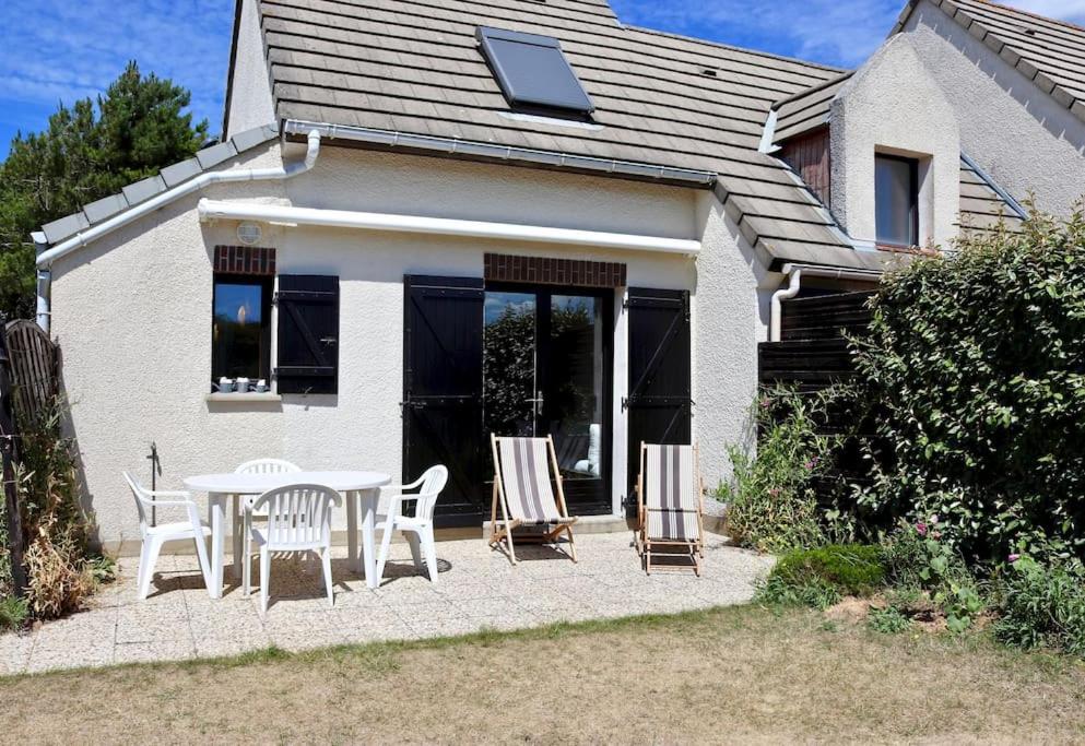 un patio con mesa y sillas frente a una casa en Cottage 4 pers, jardin plein sud, vue sur la dune, en Le Touquet-Paris-Plage