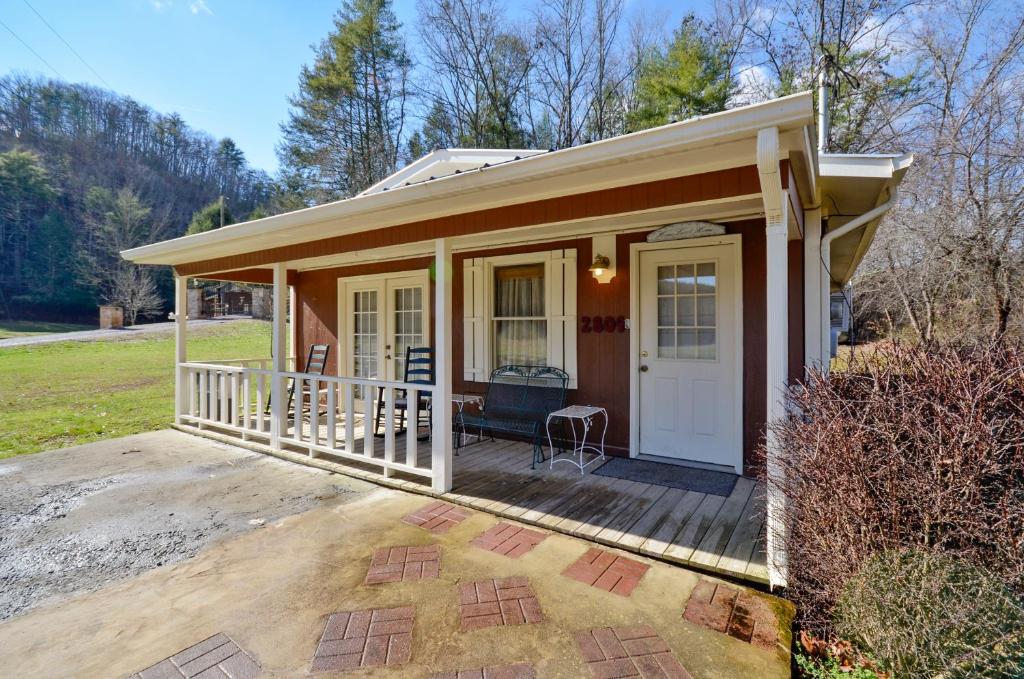 ein kleines Haus mit einer Veranda und einer weißen Tür in der Unterkunft Sweetpeas in Pigeon Forge