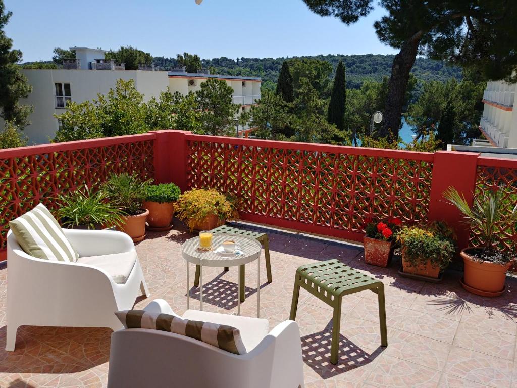 patio con sedie, tavolo e recinzione rossa di Apartment Axelle 50 METERS TO THE BEACH a Banjole