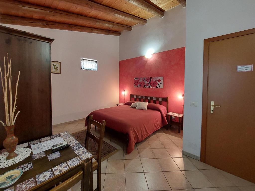 1 dormitorio con cama roja y mesa en Cloris Guest House, en Noto