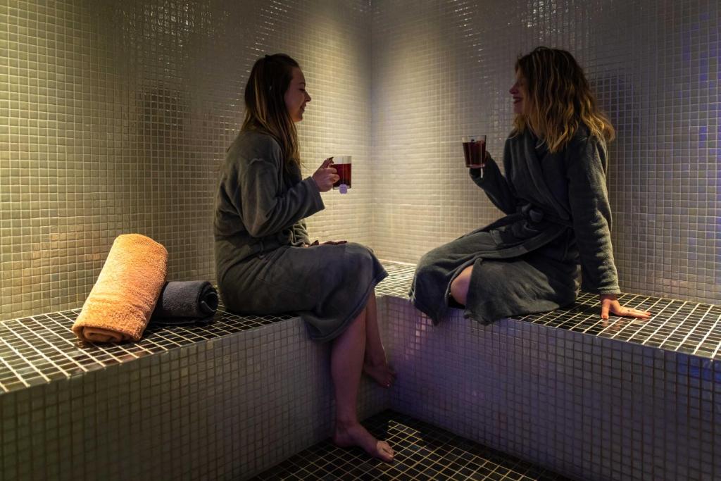 two women sitting on the backs of a public shower stall at Premantura Resort - Hotel & Restaurant in Premantura