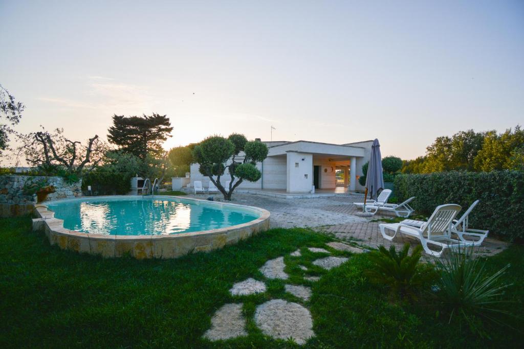 una piscina en un patio con 2 sillas y una casa en Dependance REVERSE, en Carovigno