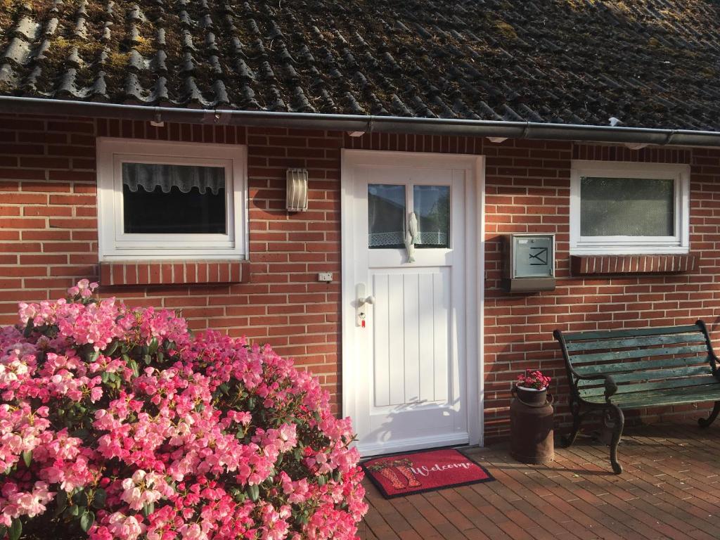 a brick house with a white door and a bench at Ferienapartment Kastanje in Groß Ippener