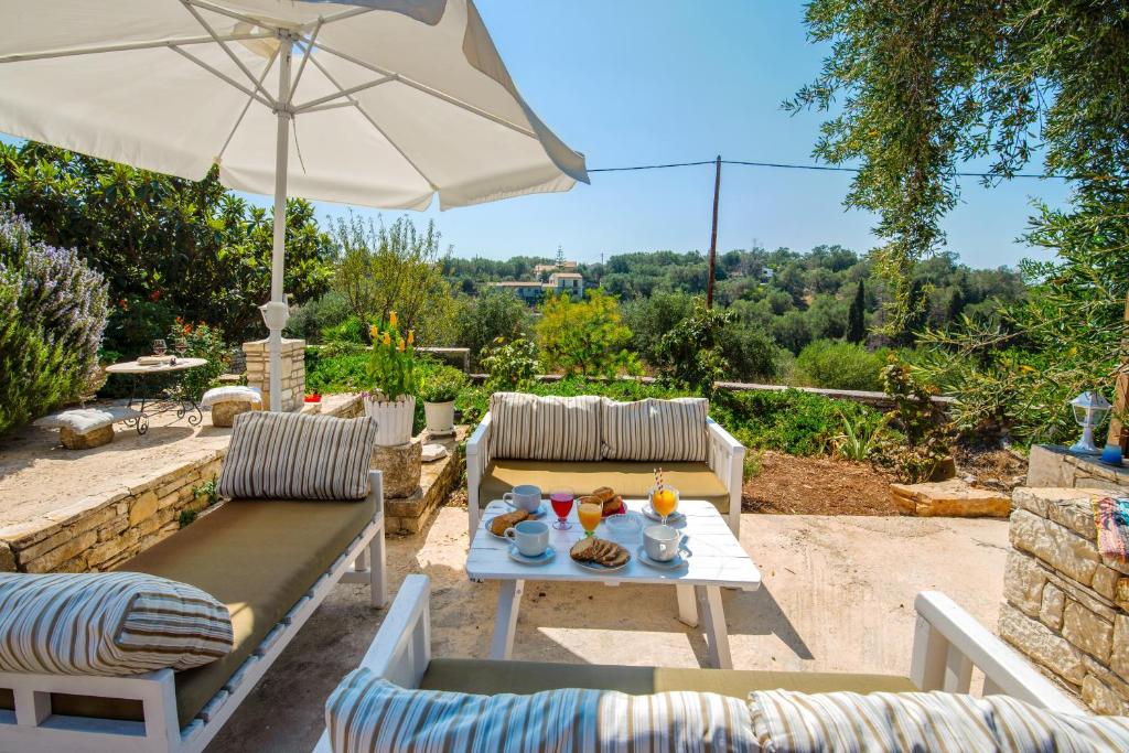 a patio with a table and chairs and an umbrella at Sterna House Paxos in Vlachopoulátika