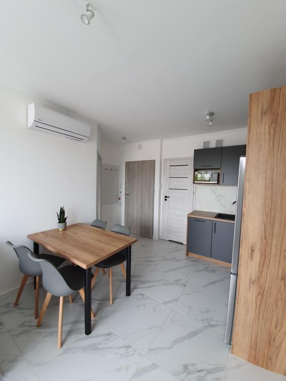 a kitchen and dining room with a wooden table and chairs at Mierzeja Park 13 apartament 40m2 in Sztutowo